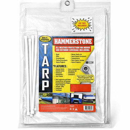 White heavy-duty tarp covering large outdoor equipment and materials
